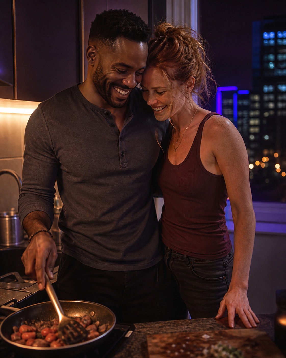A woman and man laughing together while cooking late at night