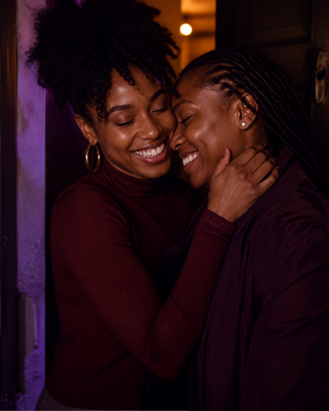 Two women laughing closely together in a doorway